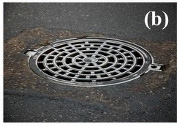 Circular metal manhole cover embedded in asphalt on a city street.
