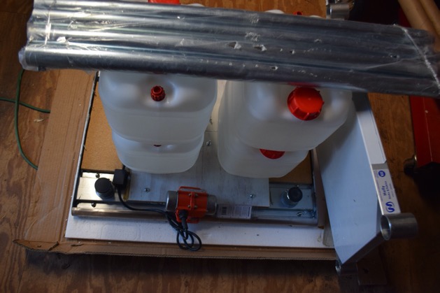 2 water-filled containers and table legs are stacked on the plywood support wood.