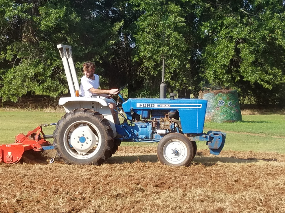 A man driving a blue tractor tilling dirt A man driving a blue tractor tilling dirt