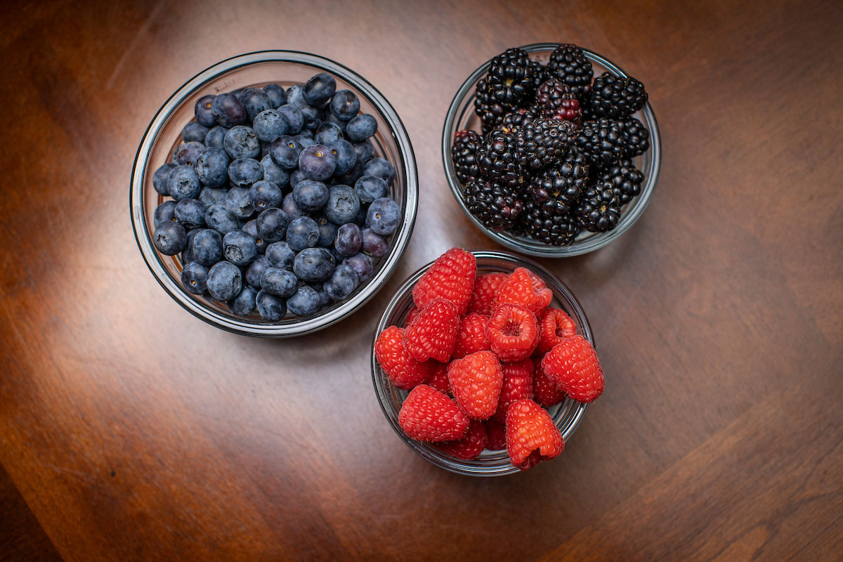 One bowl of blueberries, one bowl of raspberries and one bowl of blackberries.