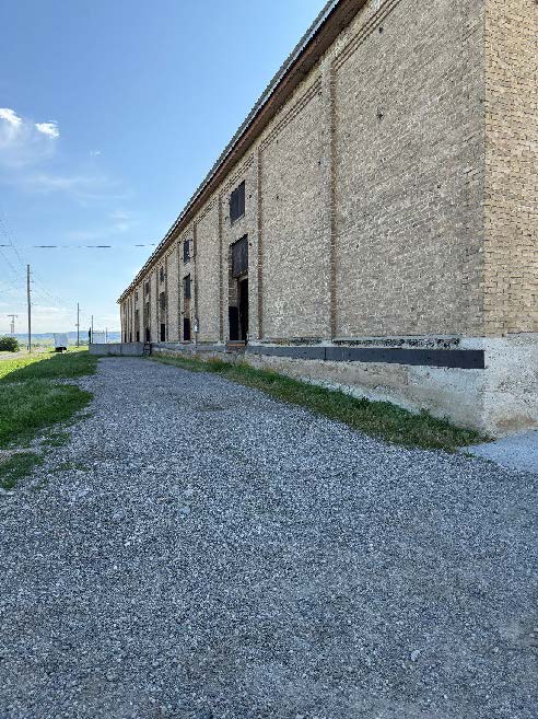 The side of a building with a gravel area to the side.