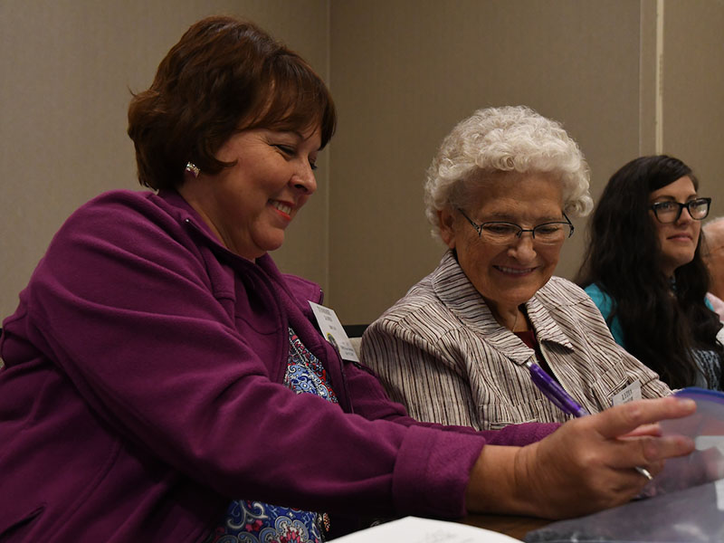 A lady setting on a desk looking at something to gether.