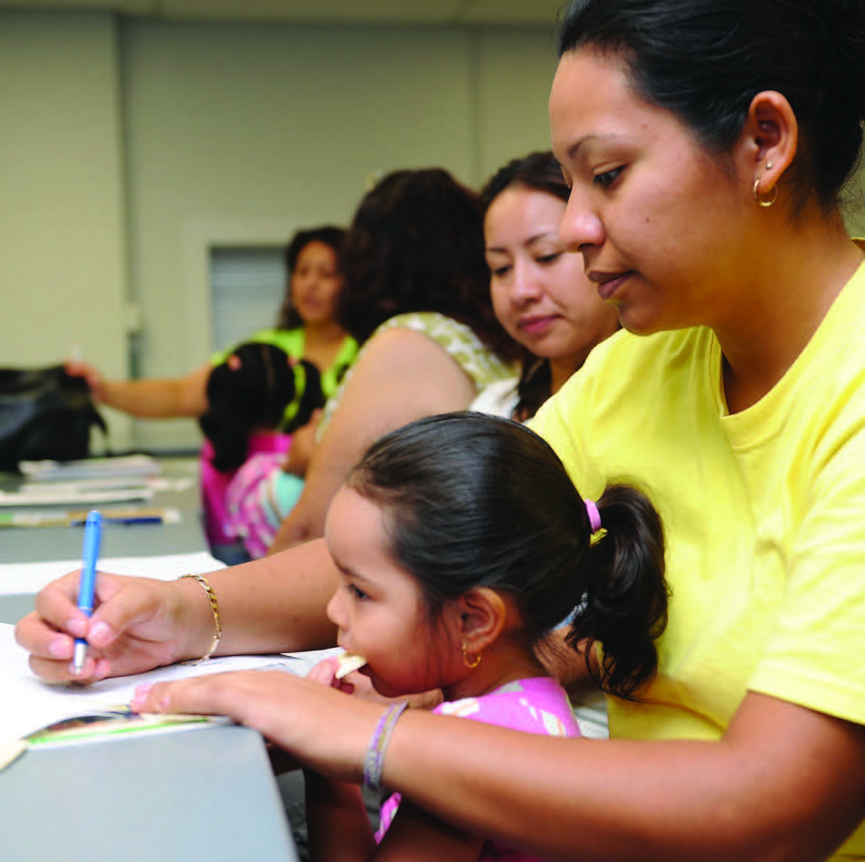 A women writing with her child in her lap.