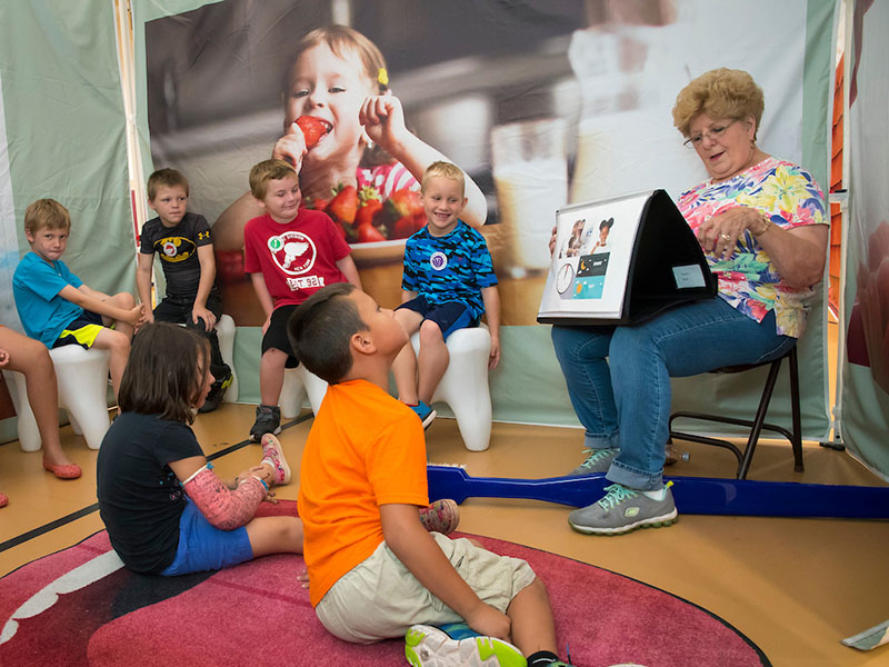 A person reading a book to students.