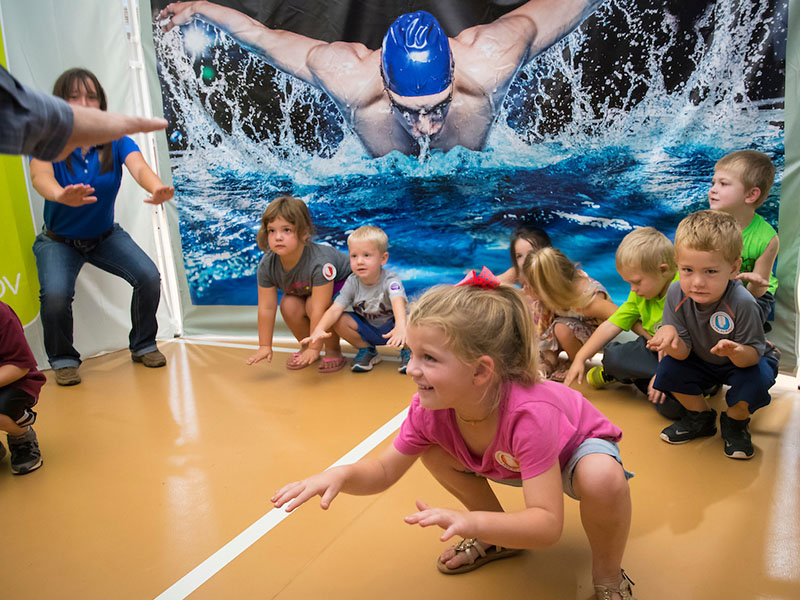 A group of kids bending their knees and stretching out their arms.