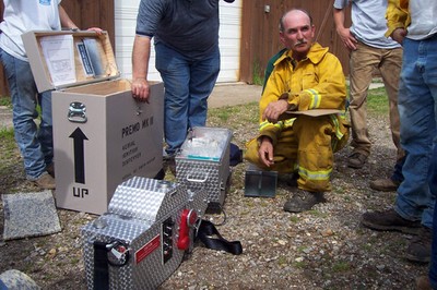 A person in a yellow fire suit showing off a silver machine. A person in a yellow fire suit showing off a silver machine.