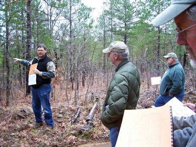 Ron Masters talking to a group of people in the forest. Ron Masters talking to a group of people in the forest.