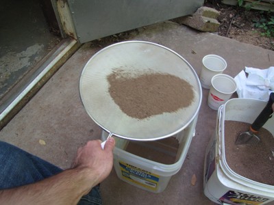 Sand being sifted through a screen into an empty bucket. Sand being sifted through a screen into an empty bucket.