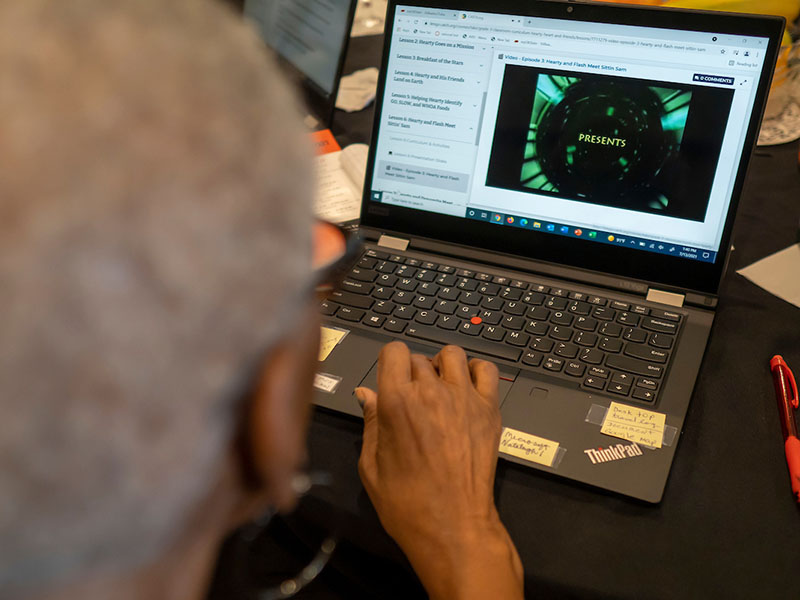A open laptop on a desk and a hand ready to type.
