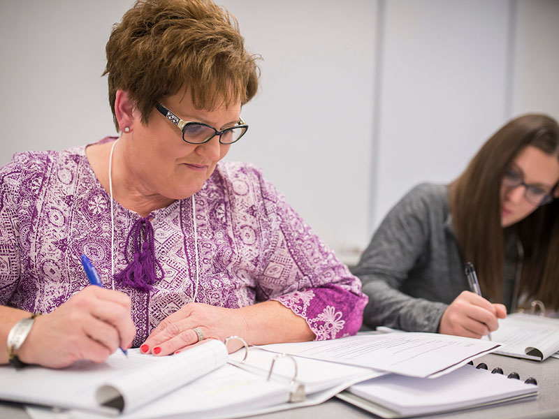 Two women setting and studying on a desk.