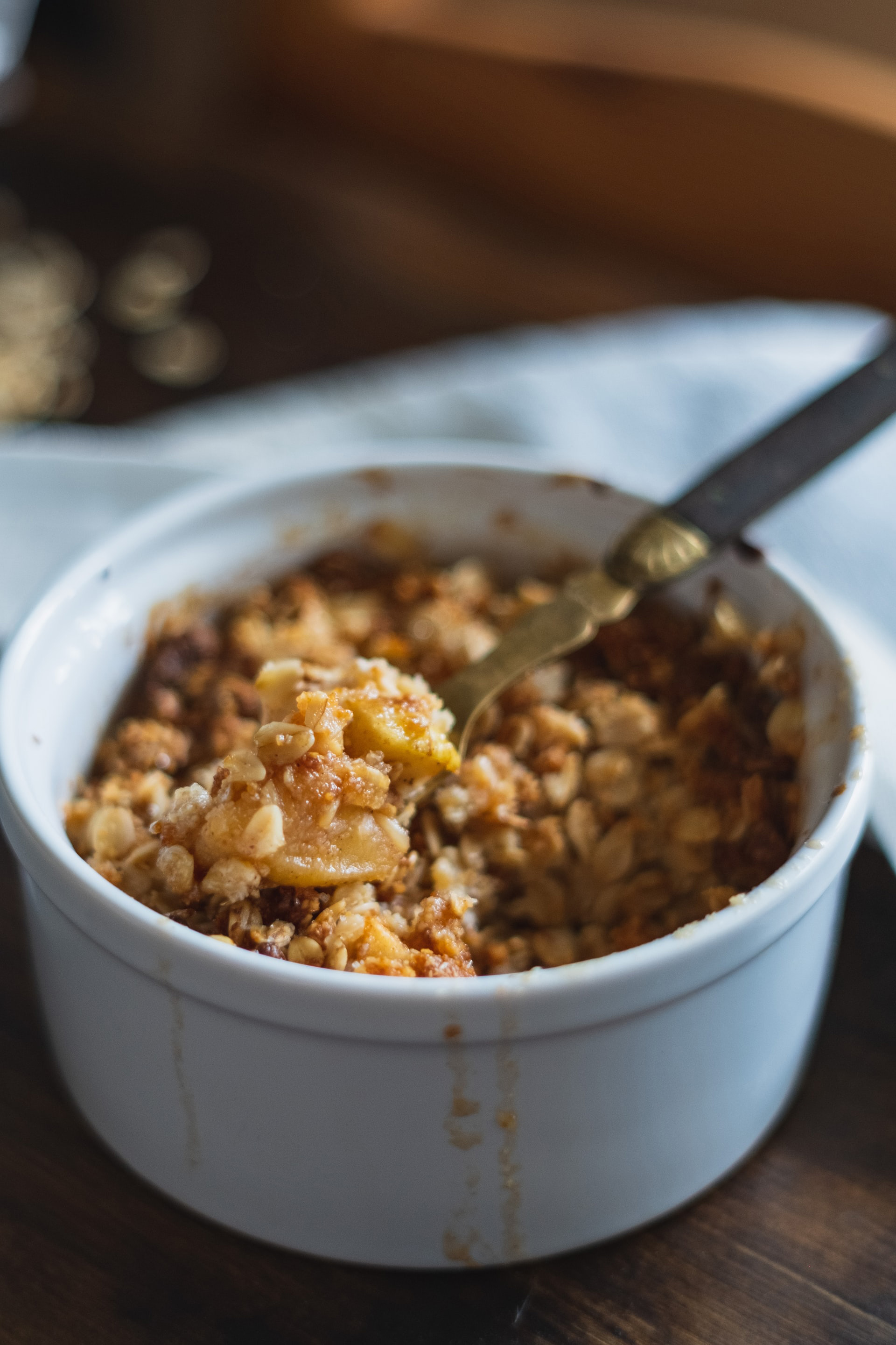 A white bowl with an apple bake and granola.
