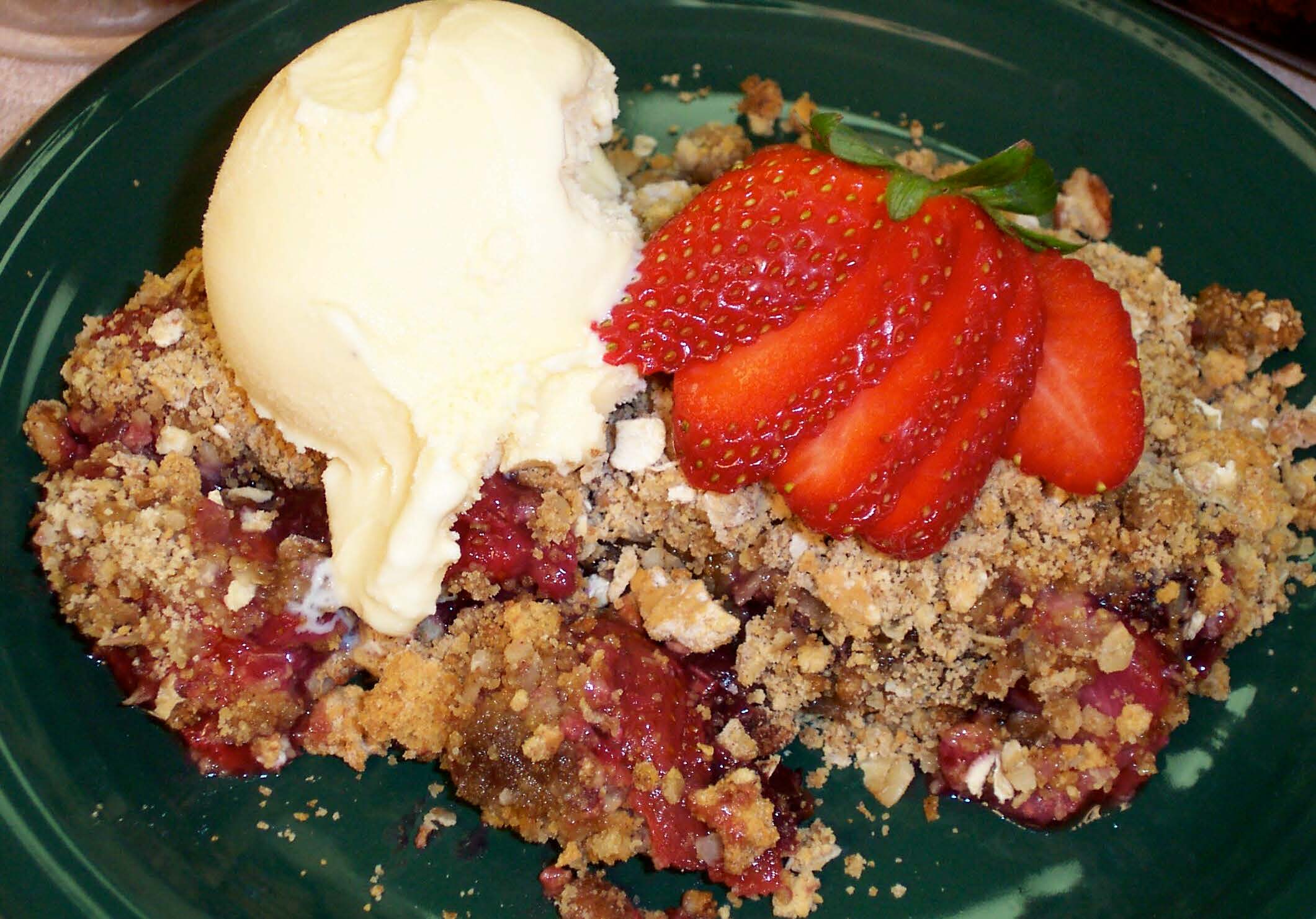 Berry crisp with ice cream on a green plate.