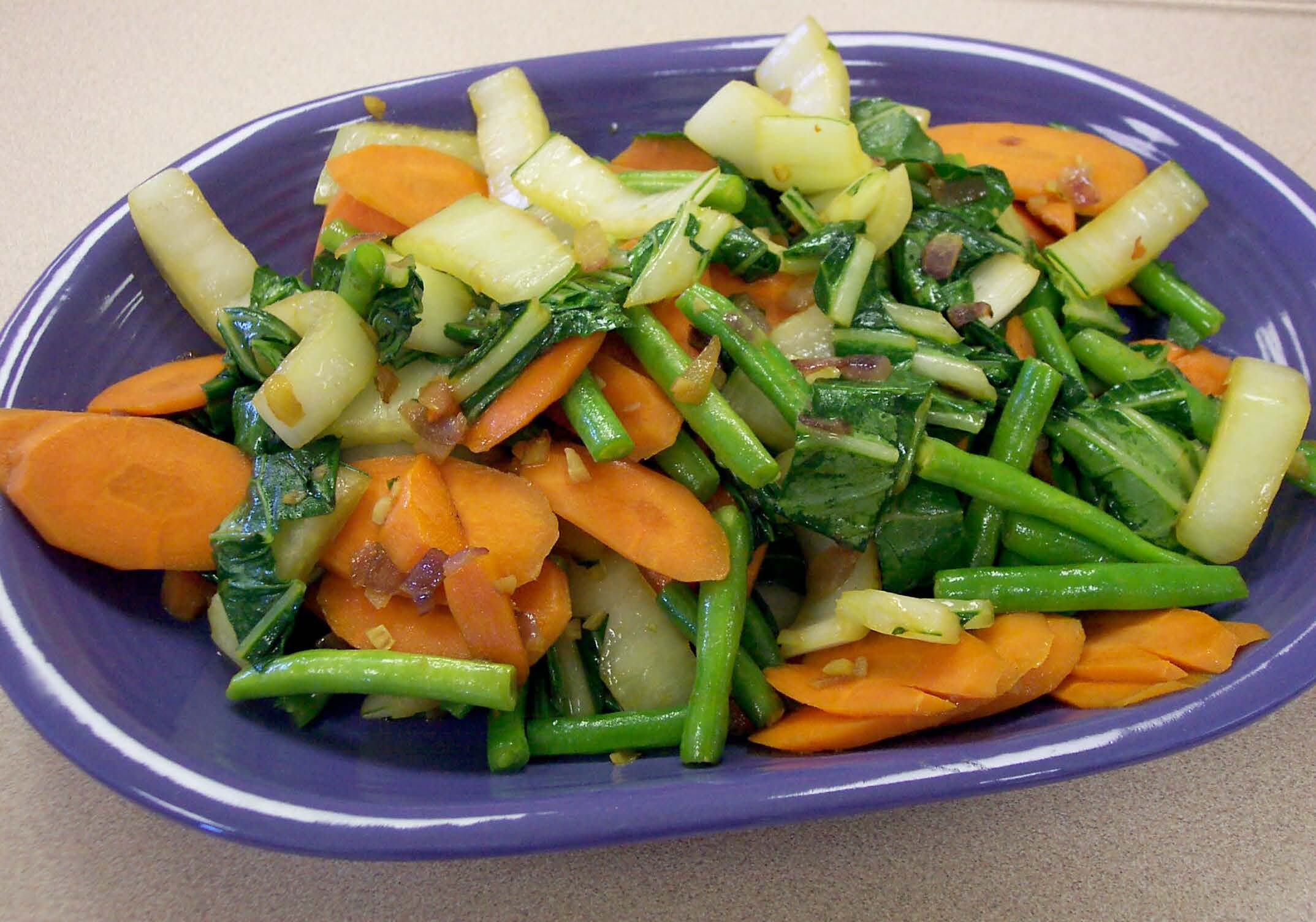 A plate of boy choy and vegetables in a blue bowl. A plate of boy choy and vegetables in a blue bowl.
