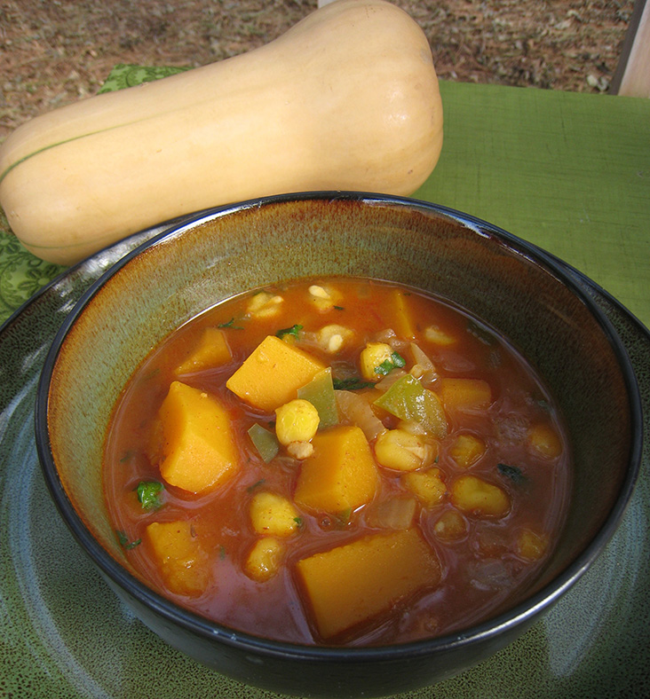 Butternut stew in a bowl with a butternut squash in the background.