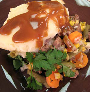 Photo of cottage pie served on a plate with gravy on top.