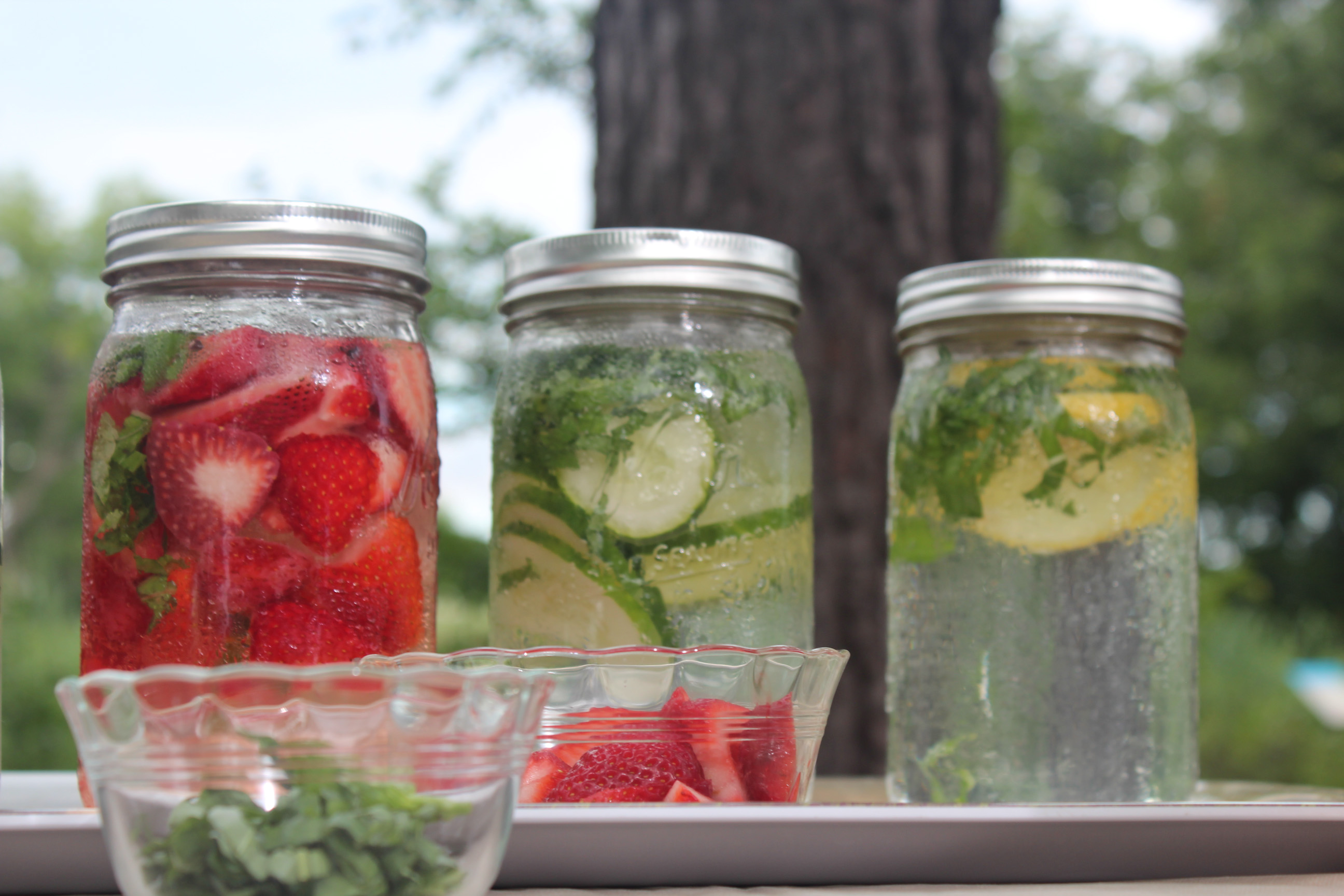 Three flavored waters in mason jars on a table. 