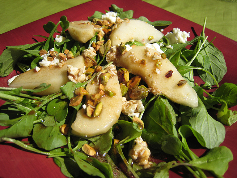 Pear and lettuce salad prepared and served on a red plate.