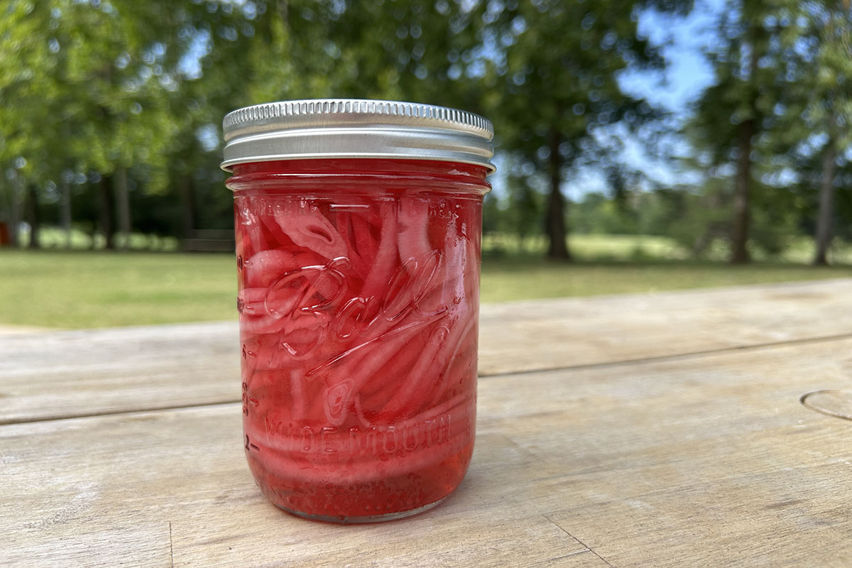 A red jar filled with pickles and onions.