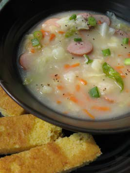Potato and cabbage chowder in a bowl with bread on the side.