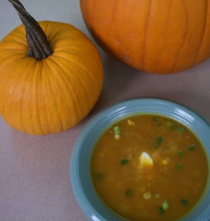 Pumpkin soup next to pumpkins. 