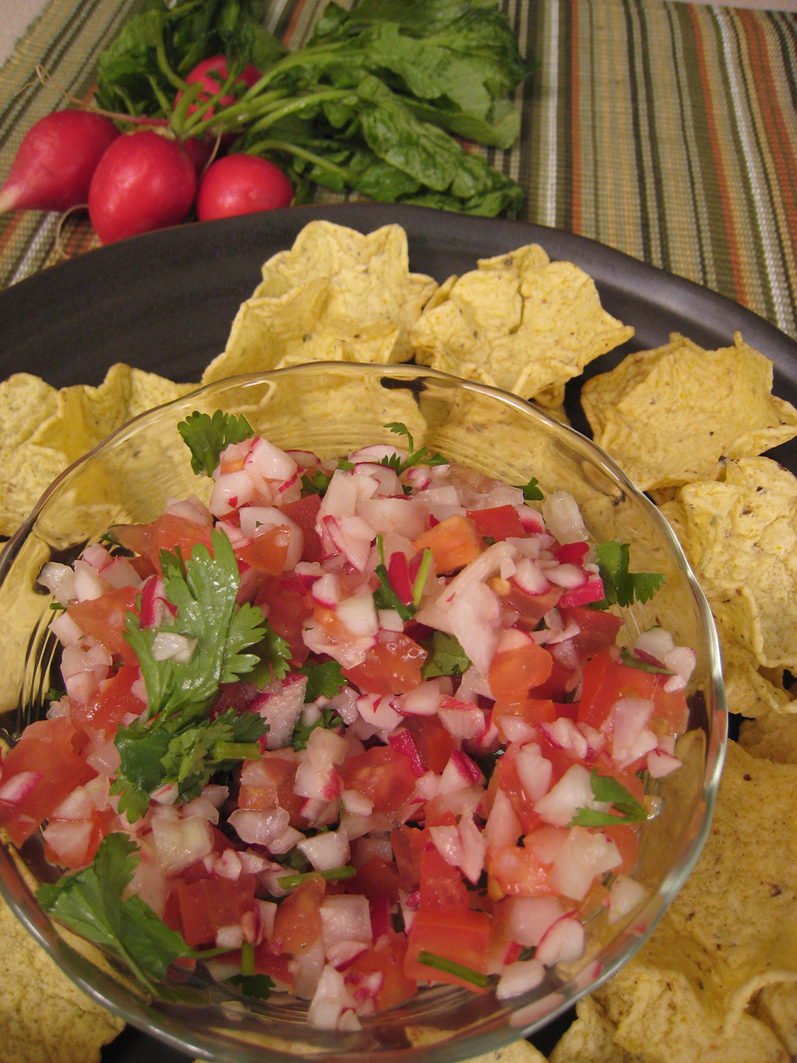 Salvadoran salsa in a bowl with chips on a plate around the bowl.