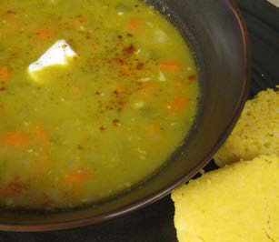 Split pea soup in a bowl with bread on the side.