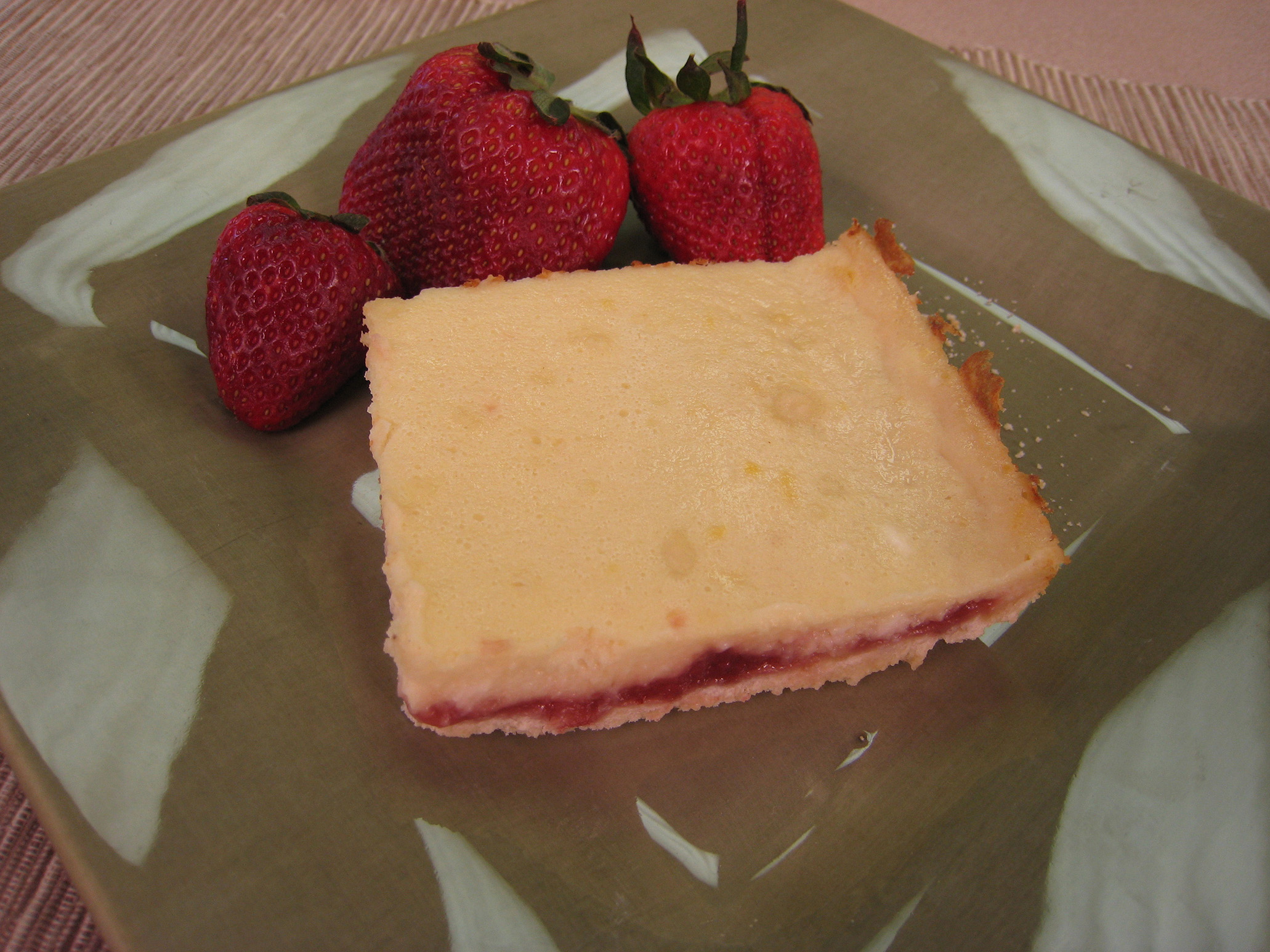 Strawberry lemon bar served on a plate with fresh strawberries.