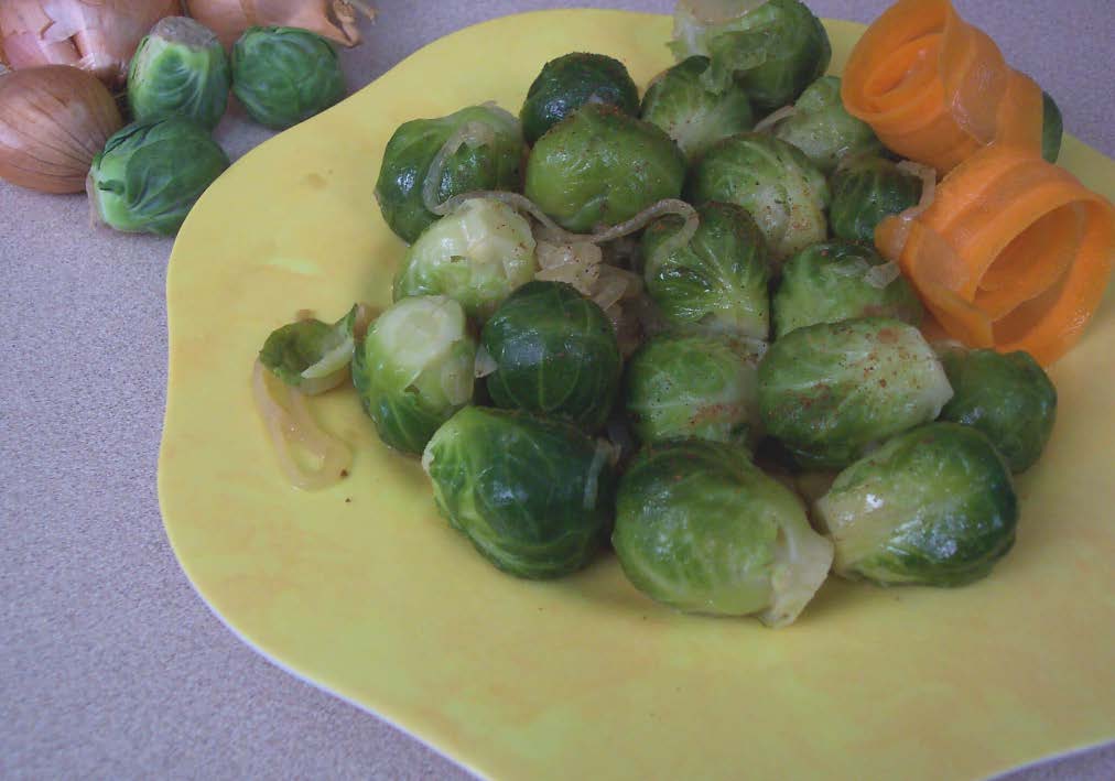 A yellow plate of cooked brussel sprouts sitting on a table.