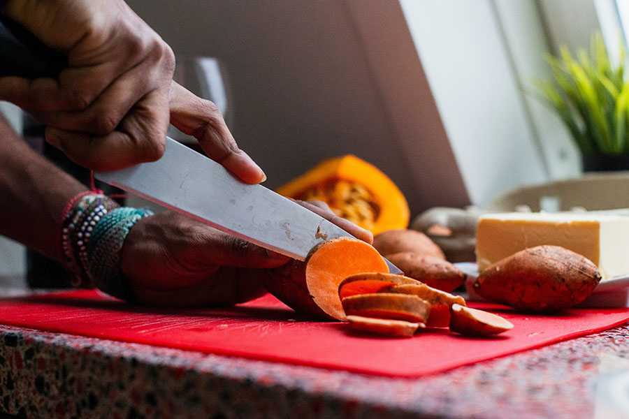 A person slicing sweet potatoes.