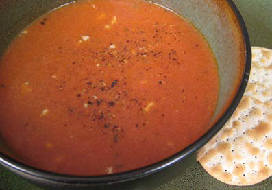 Tomato soup with blue cheese in a bowl with crackers on the side.