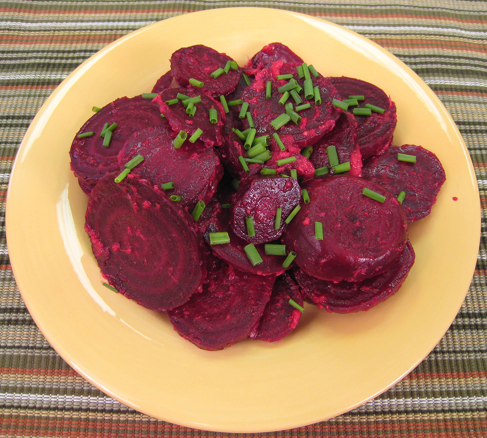Zesty beets served on a plate, garnished with chives.