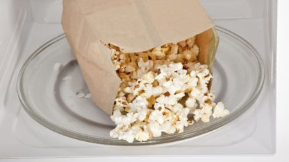 A bag of popcorn being cooking in a microwave. A bag of popcorn being cooking in a microwave.