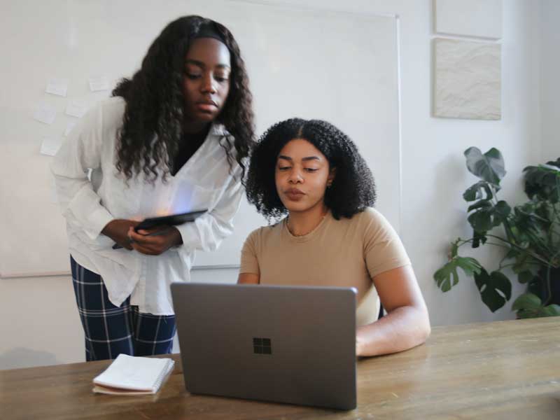Two female students sharing a laptop.