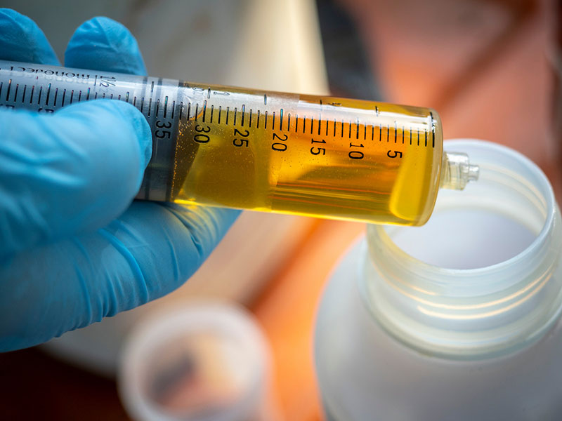 A syringe with herbicide and a white container.