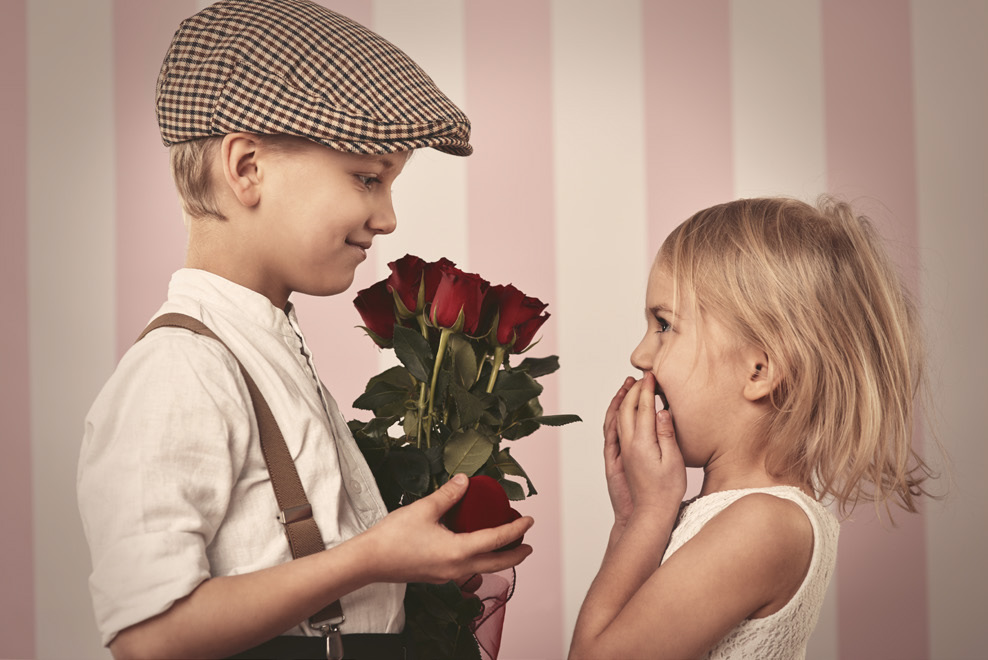 Little boy giving red roses to a little girl.