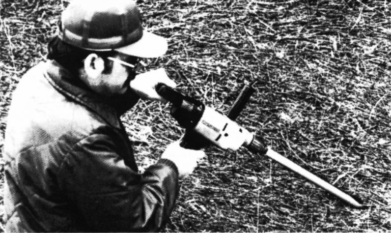 Man holding a forage probe mounted on an electric drill.