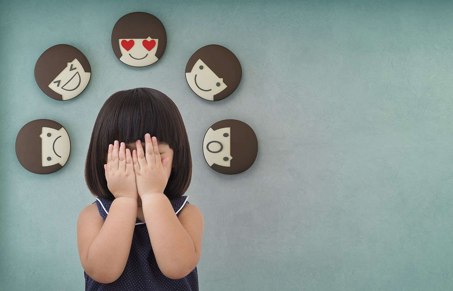 A young girl holding her hands over her face with different emotions surrounding her head.