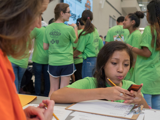 A woman watching a young girl use a calculator. A woman watching a young girl use a calculator.